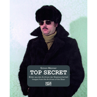 The book cover for Top Secret by Simon Menner, featuring an image from the Stasi archives. A man poses in a disguise, wearing a large black fur hat, a matching fur coat, dark sunglasses, a mustache, and a tan turtleneck sweater against a light-colored wall.