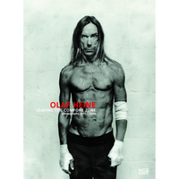 The book cover for Olaf Heine: Leaving the Comfort Zone, featuring a black-and-white photograph of musician Iggy Pop. He is shirtless with a lean, muscular physique and stands against a plain wall, staring intensely at the camera. His long hair frames his face, and his hands and left forearm are wrapped in white bandages.
