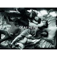 A black-and-white overhead photograph of four young men lying fully clothed on a messy bed, tangled together. The image is the cover for a book by Olaf Heine titled I Love You But I've Chosen Rock. Bright light from the right illuminates the scene with high contrast.