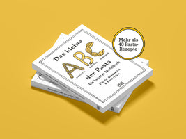 A stack of three copies of the German cookbook Das kleine ABC der Pasta, fanned out on a solid mustard-yellow background. The white cover has black, hand-drawn text and illustrations, with the letters A, B, and C formed from different pasta shapes. A yellow circle advertises more than 40 pasta recipes.