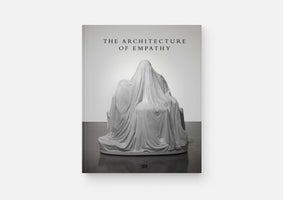A book titled The Architecture of Empathy by Hatje Cantz, set against a white background. The cover features a black and white photograph of a sculpture showing a figure seated on a throne, entirely concealed beneath a draped white sheet.