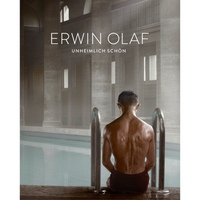 A poster for an Erwin Olaf exhibition titled Unheimlich Schön, featuring a photograph of a man seen from the back, his skin wet and glistening. He is sitting on the edge of a steamy indoor swimming pool in a grand hall with large stone pillars.