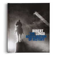A hardback book titled Robert Longo: The Acceleration of History. The cover features a dramatic, black-and-white photograph of a silhouetted equestrian statue on a pedestal, illuminated from below against a dark, hazy background. A crane arm with a hook is visible in the upper right. The author's name in white is layered over the title in blue.