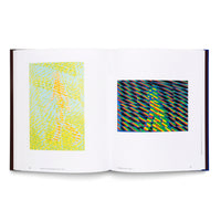 An open art book with a dark cover displayed against a white background. The two-page spread features two colorful, abstract op-art style prints of a walking figure. The left image is yellow, orange, and light blue, while the right image shows a figure against a vibrant pattern of black and rainbow-colored diagonal stripes.