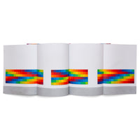 An eye-level, studio shot of a concertina-style book standing open on a white surface. The white pages feature a continuous horizontal band of small, brightly colored squares in a rainbow spectrum, positioned above a solid grey band at the bottom.