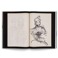 An open, spiral-bound sketchbook on a white background. The left page has a faint pencil sketch of a man and a woman wearing hats. The right page features a bold, gestural ink drawing of a figure with an elaborate updo, rendered in energetic, scribbled black lines.