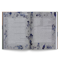 A double-page spread from a book featuring columns of black text. The pages are framed and filled with dynamic blue and black ink wash illustrations depicting stylized figures, mostly women, in chaotic and dreamlike bistro scenes.