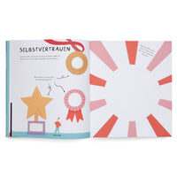 An open children's activity book in German shows a two-page spread about self-confidence. The left page, titled SELBSTVERTRAUEN, features illustrations of a medal, a trophy, and a rosette with prompts for the reader to write down their skills. The right page has a blank circular space surrounded by a red and pink sunburst pattern, inviting the reader to draw a picture of something they are proud of.