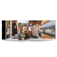 An open photobook on a white surface displays a two-page spread featuring a collage of four color photographs. From left to right, the images show a Venetian mask shop, people on a boat, a man's back covered in a large tattoo of Italian landmarks, and an aerial view of the Venice skyline including the Doge's Palace.