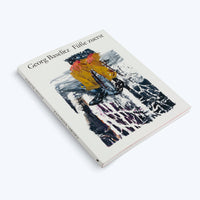 A white paperback book titled Georg Baselitz Füße zuerst, lying at an angle on a white background. The cover features an expressive, abstract painting of a figure's lower half in bright yellow trousers and black boots, set against a chaotic background of black, white, and grey brushstrokes.
