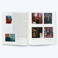 A high-angle shot of an open art book on a white surface. The book shows a two-page spread with German text and five color reproductions of expressionist paintings. The left page has a portrait of an older man, while the right page displays four paintings of figures and abstract forms.