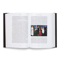 An open hardcover book with black covers is seen from above on a white surface. The pages contain German text, and the right-hand page features a color reproduction of the expressionist painting The Dance of Life by Edvard Munch.
